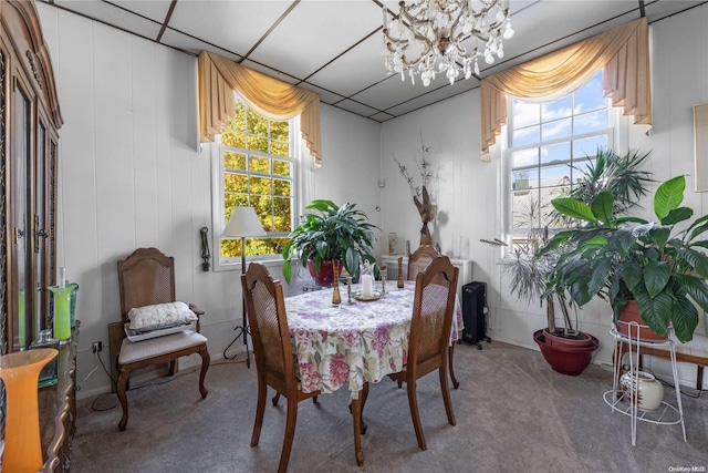 carpeted dining area with a drop ceiling and a chandelier