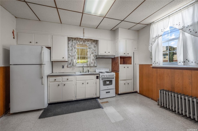 kitchen featuring a drop ceiling, white appliances, white cabinets, sink, and radiator heating unit