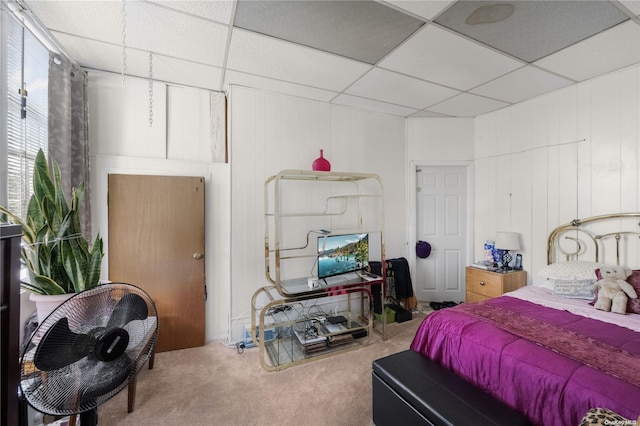 carpeted bedroom with wood walls and a drop ceiling