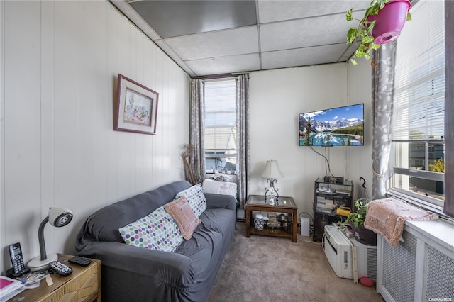 carpeted living room featuring wood walls