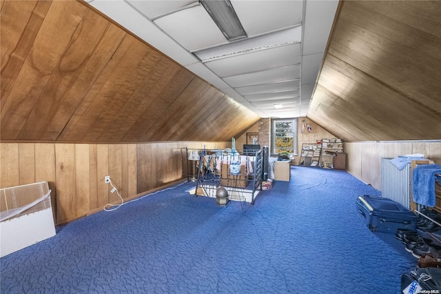 additional living space featuring carpet flooring, lofted ceiling, and wooden walls