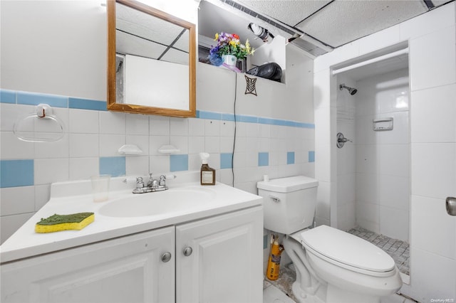 bathroom with vanity, toilet, tile walls, and a tile shower