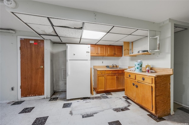 kitchen with decorative backsplash, white refrigerator, a drop ceiling, and sink