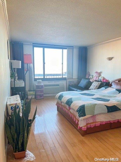 bedroom featuring hardwood / wood-style floors, a textured ceiling, and ornamental molding