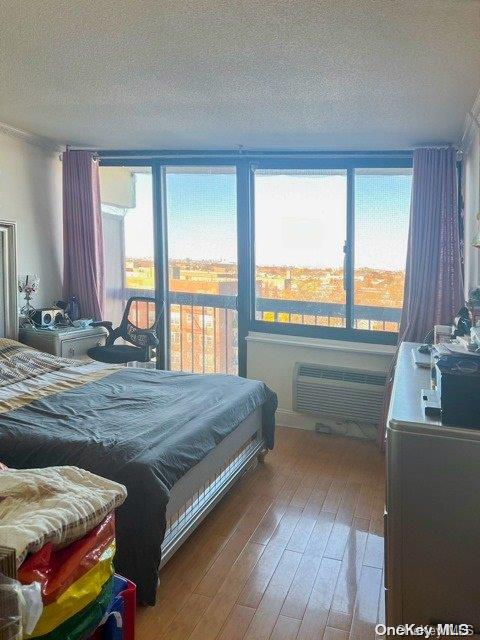 bedroom featuring hardwood / wood-style flooring, a textured ceiling, and a wall mounted AC