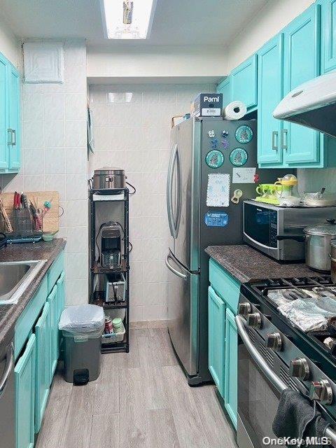 kitchen featuring appliances with stainless steel finishes, light hardwood / wood-style floors, and blue cabinets