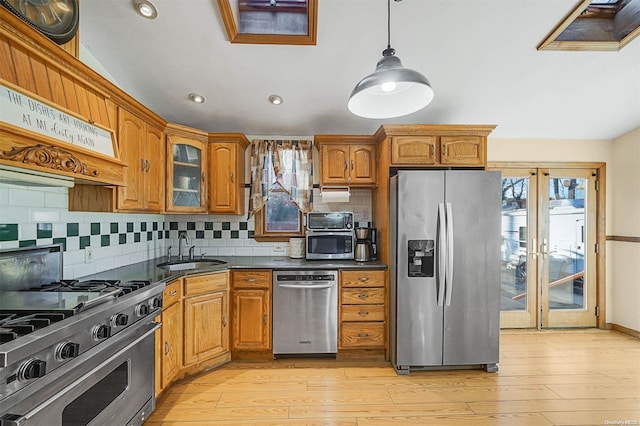 kitchen featuring appliances with stainless steel finishes, decorative light fixtures, light hardwood / wood-style flooring, and sink