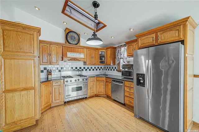 kitchen featuring sink, hanging light fixtures, vaulted ceiling, light wood-type flooring, and stainless steel appliances