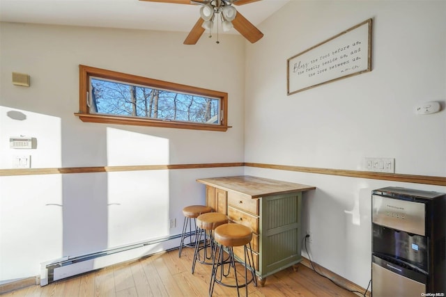 interior space featuring a baseboard radiator, wooden counters, green cabinetry, lofted ceiling, and light wood-type flooring