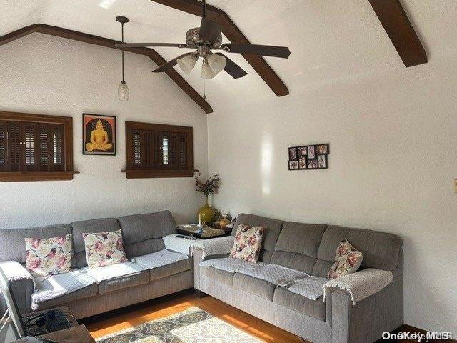 living room featuring ceiling fan, lofted ceiling with beams, and wood-type flooring