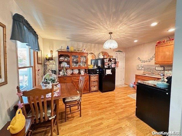 kitchen featuring hanging light fixtures, black fridge, sink, and light hardwood / wood-style floors