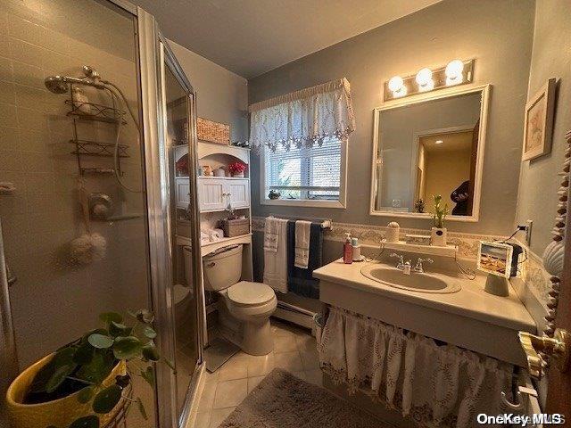 bathroom with a shower with door, vanity, tile patterned flooring, and toilet