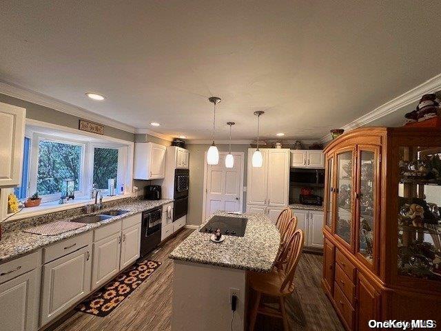 kitchen featuring sink, decorative light fixtures, white cabinets, and a kitchen island