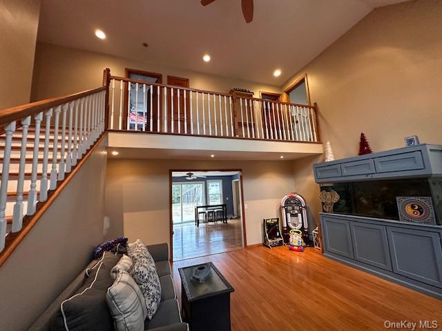 living room with a high ceiling, wood-type flooring, and ceiling fan