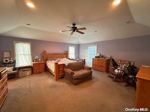 carpeted bedroom featuring vaulted ceiling, a raised ceiling, and ceiling fan