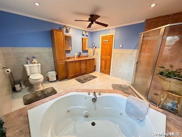 full bath featuring toilet, tile walls, a tub with jets, a stall shower, and crown molding