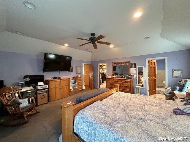 bedroom with dark colored carpet, vaulted ceiling, connected bathroom, and ceiling fan