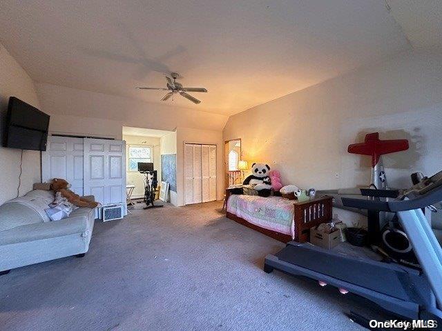 bedroom with multiple closets, vaulted ceiling, and ceiling fan