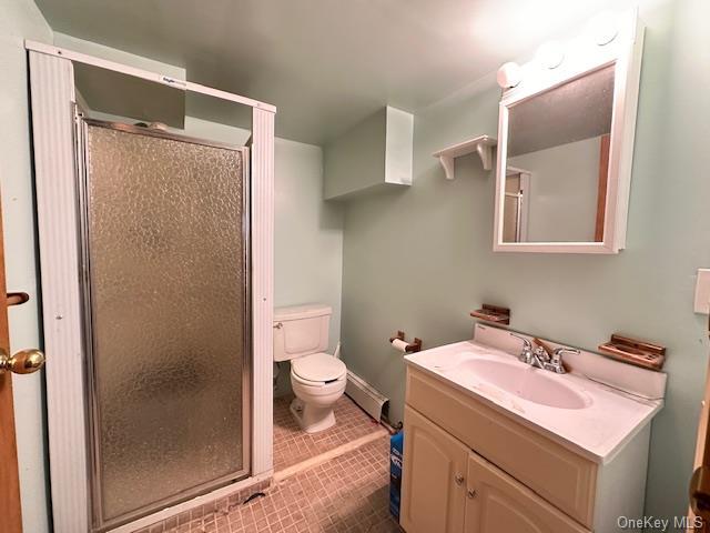 bathroom with a baseboard radiator, vanity, walk in shower, toilet, and tile patterned floors