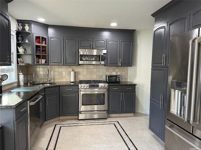 kitchen with dark stone countertops, decorative backsplash, sink, and stainless steel appliances