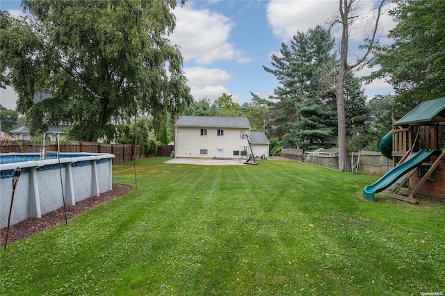 view of yard featuring a patio area, a fenced in pool, and a playground