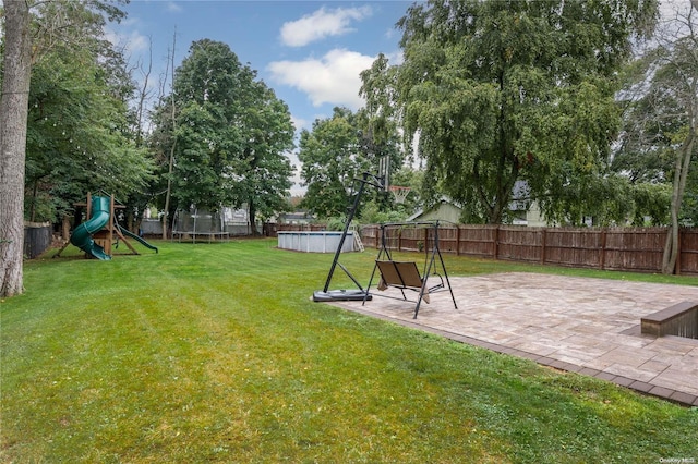 view of yard with a trampoline, a playground, a patio area, and a fenced in pool