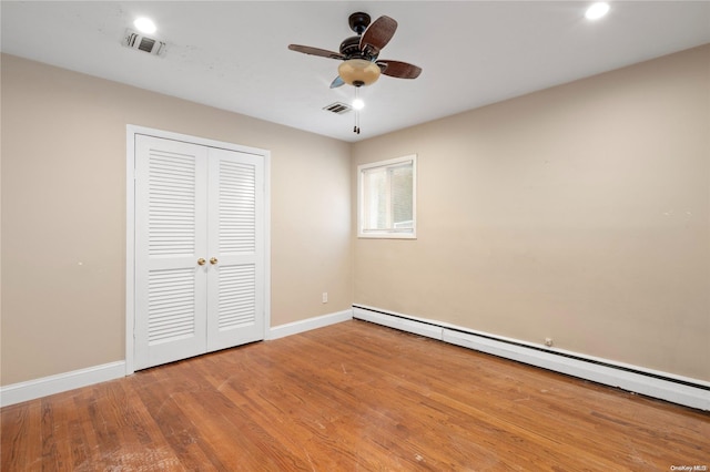 unfurnished bedroom with hardwood / wood-style floors, ceiling fan, a closet, and a baseboard heating unit