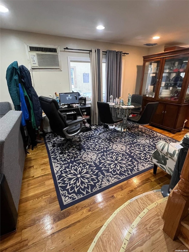 living room with a wall mounted air conditioner and light hardwood / wood-style floors