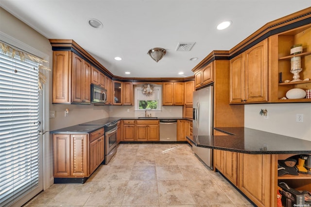 kitchen with appliances with stainless steel finishes, kitchen peninsula, sink, and dark stone counters