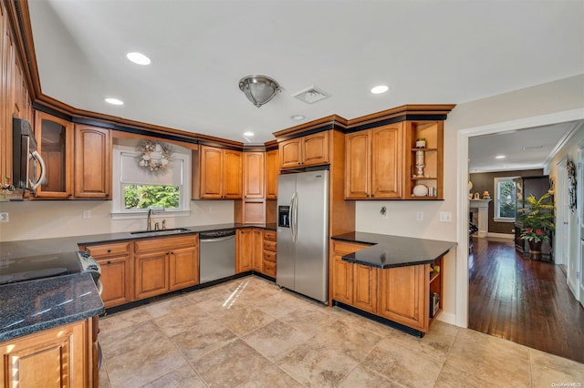 kitchen featuring stainless steel appliances, kitchen peninsula, sink, and dark stone countertops