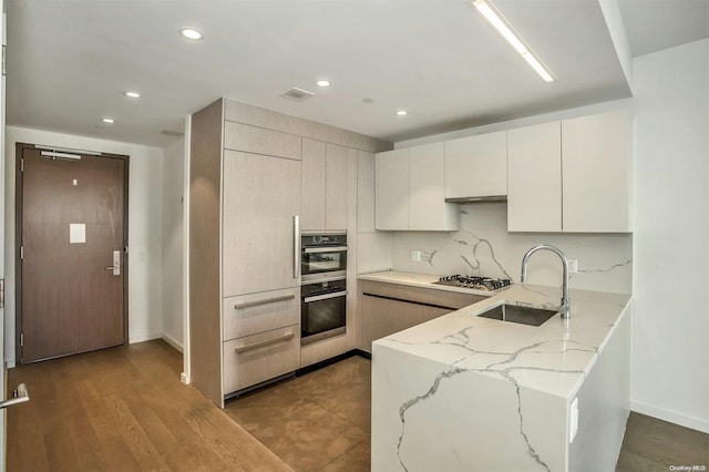 kitchen with light stone countertops, sink, stainless steel appliances, dark hardwood / wood-style floors, and decorative backsplash