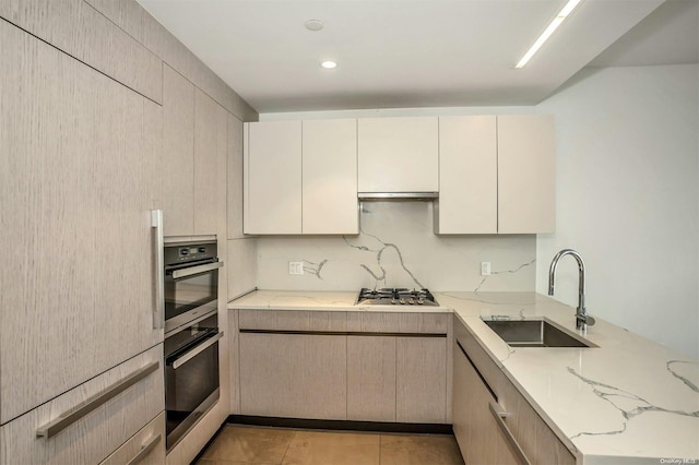 kitchen featuring light stone countertops, light tile patterned floors, appliances with stainless steel finishes, and sink