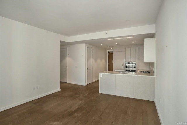 kitchen featuring sink, stainless steel appliances, dark wood-type flooring, kitchen peninsula, and white cabinets