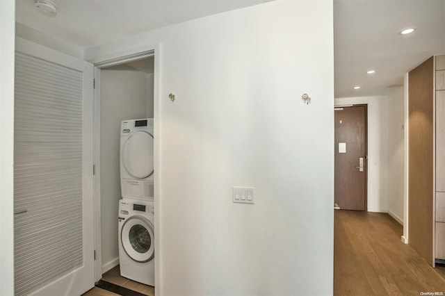 washroom with light hardwood / wood-style floors and stacked washer / drying machine