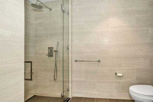 bathroom featuring tile patterned floors, a shower with door, and toilet