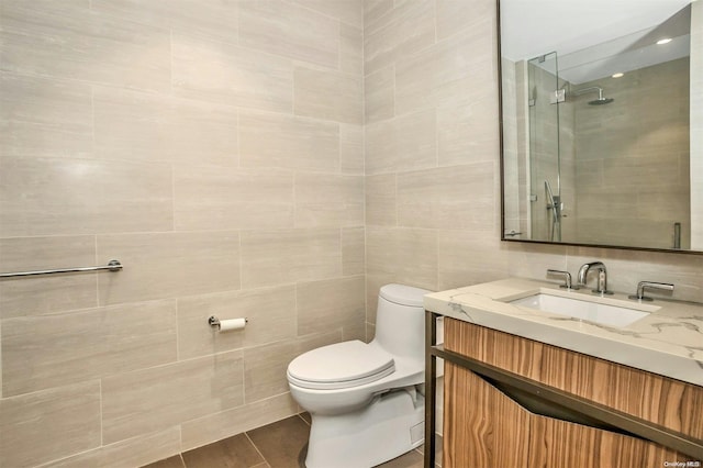 bathroom featuring tile patterned floors, walk in shower, vanity, tile walls, and toilet