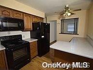 kitchen featuring ceiling fan, black appliances, and light wood-type flooring