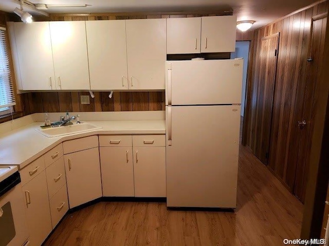 kitchen with white cabinetry, sink, white appliances, and light hardwood / wood-style flooring