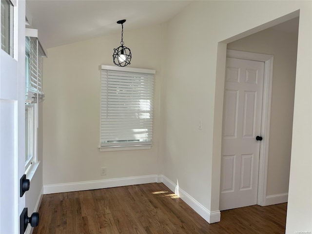 unfurnished dining area featuring baseboards, dark wood-style flooring, and vaulted ceiling