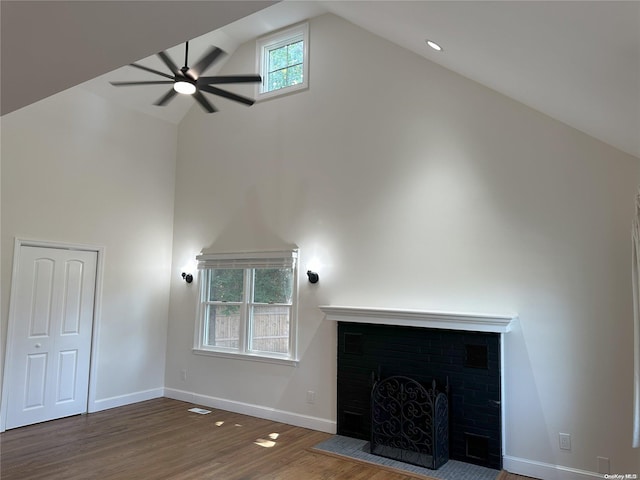 unfurnished living room featuring high vaulted ceiling, a healthy amount of sunlight, dark hardwood / wood-style floors, and a brick fireplace