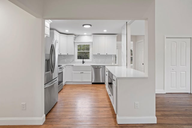 kitchen featuring light wood-style flooring, a sink, stainless steel appliances, light countertops, and white cabinets