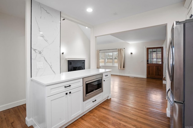 kitchen with light wood-style flooring, light countertops, appliances with stainless steel finishes, white cabinetry, and open floor plan