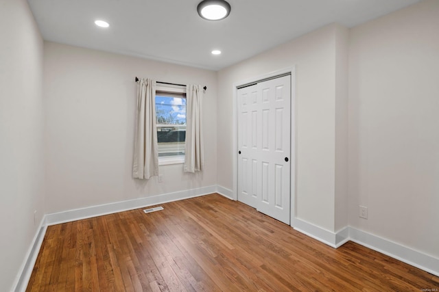 unfurnished room with visible vents, baseboards, and hardwood / wood-style floors