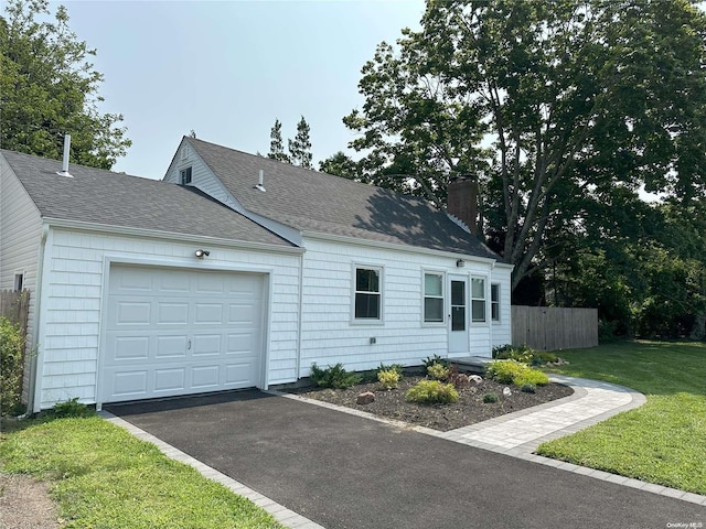 view of front of house featuring a front lawn, fence, roof with shingles, a garage, and a chimney