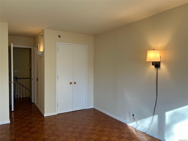 unfurnished bedroom with dark parquet flooring and a closet