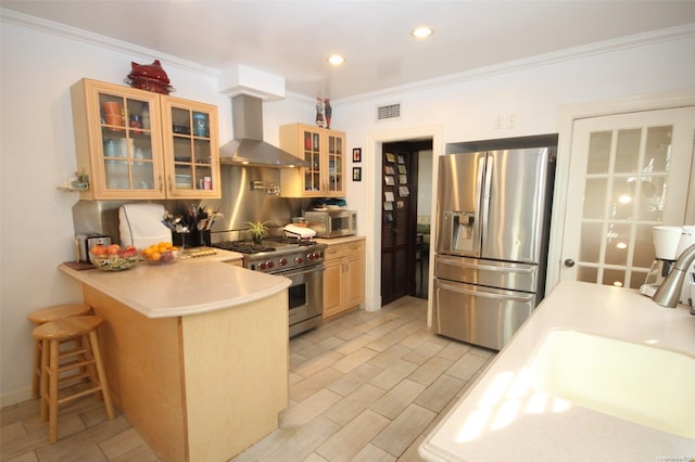 kitchen with a kitchen breakfast bar, sink, wall chimney exhaust hood, appliances with stainless steel finishes, and kitchen peninsula