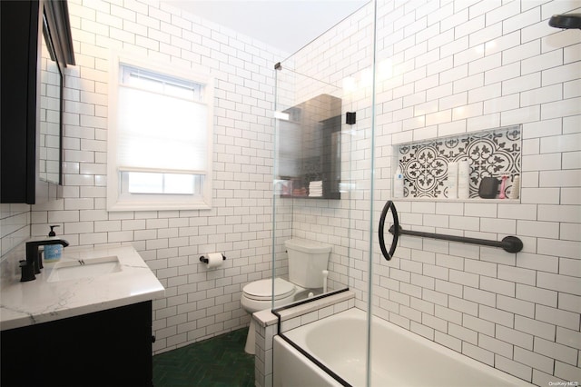 full bathroom featuring tiled shower / bath, vanity, toilet, and tile walls