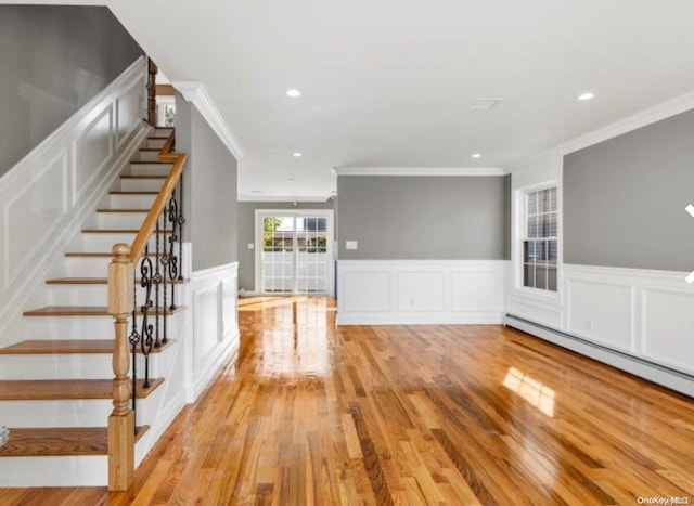 unfurnished living room with baseboard heating, crown molding, and light hardwood / wood-style flooring