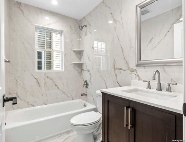 full bathroom featuring tiled shower / bath, vanity, toilet, and tile walls