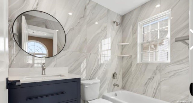 full bathroom featuring tiled shower / bath combo, toilet, tile walls, and vanity